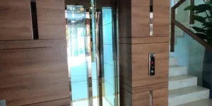 Elegant home elevator with glass doors integrated into a modern wooden wall paneling in a luxury apartment.